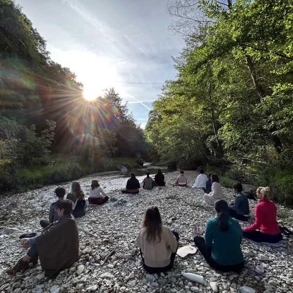 Groupe de stagiaires en méditation au soleil au bord de l'eau lors de notre week-end rencontre.